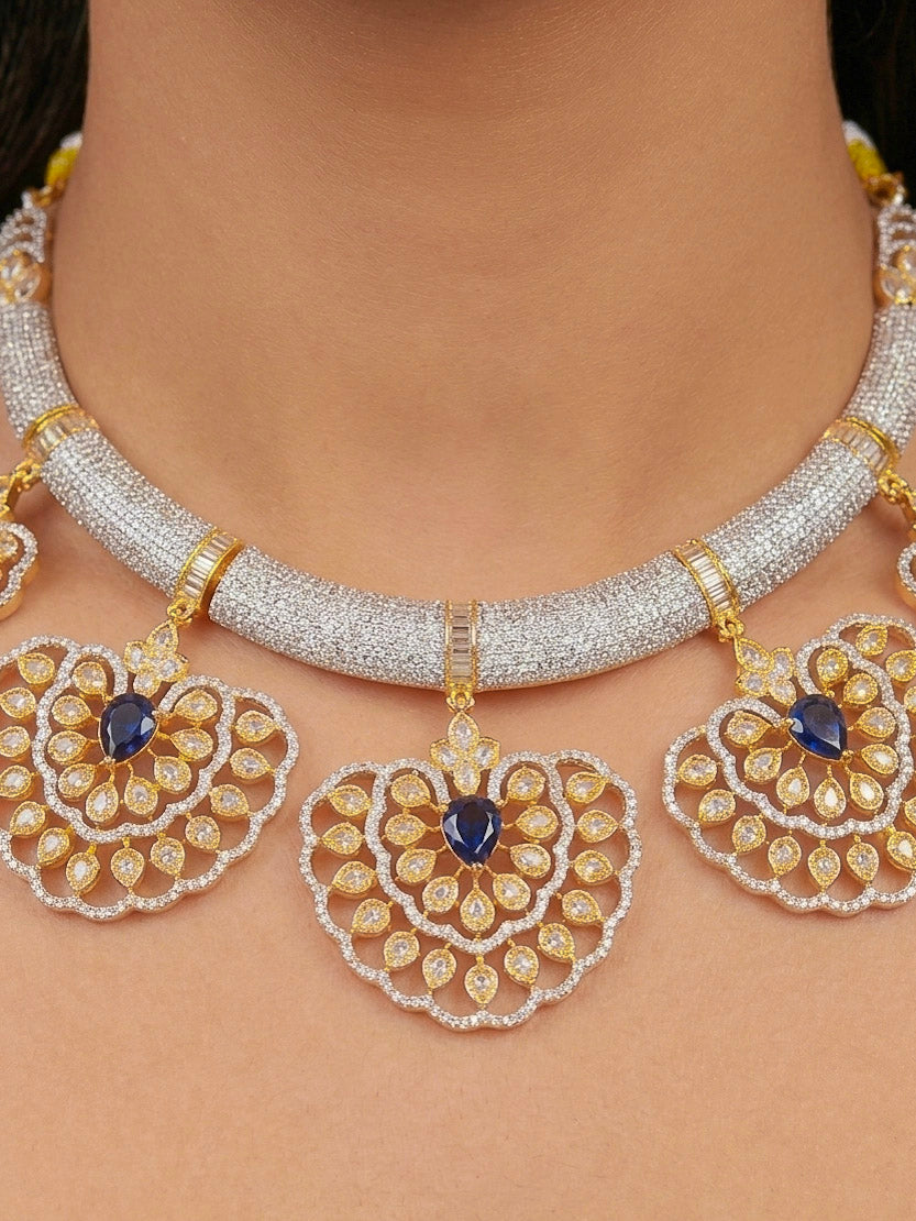 Close-up of a woman wearing an ornate Western American diamond Raizel Blue Necklace Set (Dual Tone) Collar jewellery set and earrings with Colored Stone and American Diamond. Bride-to-be styled in a premium American diamond artificial necklace for her reception party.