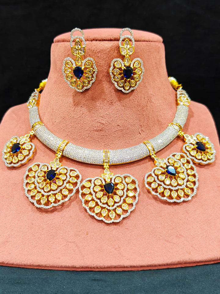 Close-up of an ornate Western American diamond Raizel Blue Necklace Set (Dual Tone) Collar jewellery set and earrings with Colored Stone and American Diamond. Close-up of a cocktail party look featuring a premium American diamond necklace.