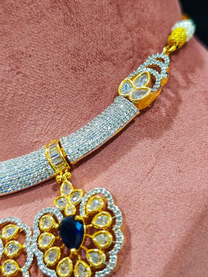 Close-up of an ornate Western American diamond Raizel Blue Necklace Set (Dual Tone) Collar jewellery set and earrings with Colored Stone and American Diamond. Close-up of a cocktail party look featuring a premium American diamond necklace.