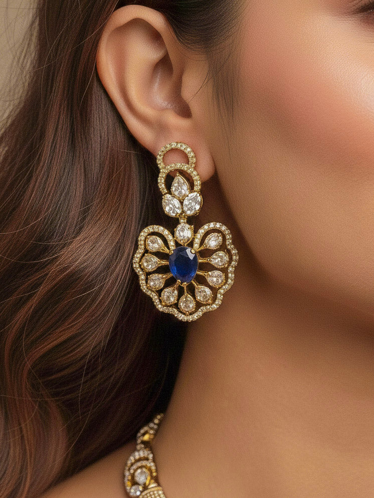 Close-up of a woman wearing an ornate Western American diamond Raizel Blue Necklace Set (Mehendi Polish) Collar jewellery set and earrings with Colored Stone and American Diamond. Reception-ready look featuring a statement American diamond jewelry set.