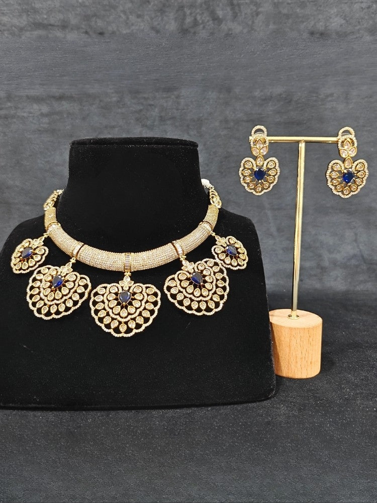 Close-up of an ornate Western American diamond Raizel Blue Necklace Set (Mehendi Polish) Collar jewellery set and earrings with Colored Stone and American Diamond. Reception-ready look featuring a statement American diamond jewelry set.