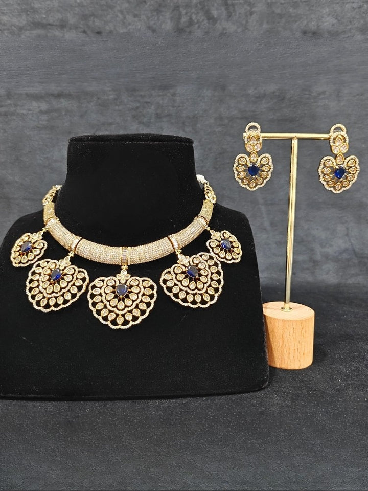Close-up of an ornate Western American diamond Raizel Blue Necklace Set (Mehendi Polish) Collar jewellery set and earrings with Colored Stone and American Diamond. Reception-ready look featuring a statement American diamond jewelry set.