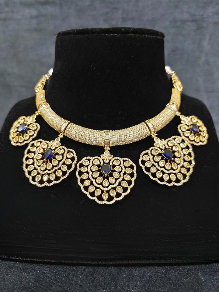 Close-up of an ornate Western American diamond Raizel Blue Necklace Set (Mehendi Polish) Collar jewellery set and earrings with Colored Stone and American Diamond. Reception-ready look featuring a statement American diamond jewelry set.