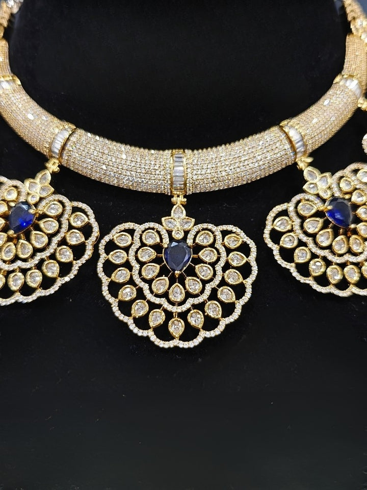 Close-up of an ornate Western American diamond Raizel Blue Necklace Set (Mehendi Polish) Collar jewellery set and earrings with Colored Stone and American Diamond. Reception-ready look featuring a statement American diamond jewelry set.