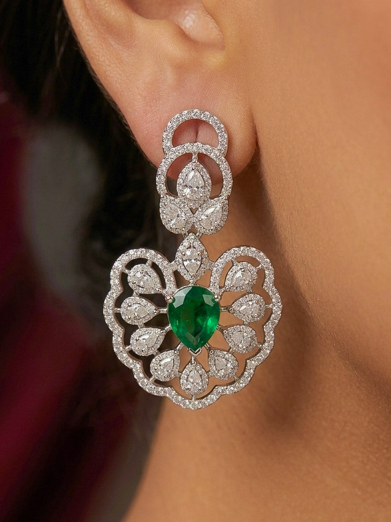 Close-up of a woman wearing an ornate Western American diamond Raizel Emerald Green Necklace Set(Silver Polish) Collar jewellery set and earrings with  Colored Stone and American Diamond. Bride-to-be styled in a premium American diamond artificial necklace for her reception party.