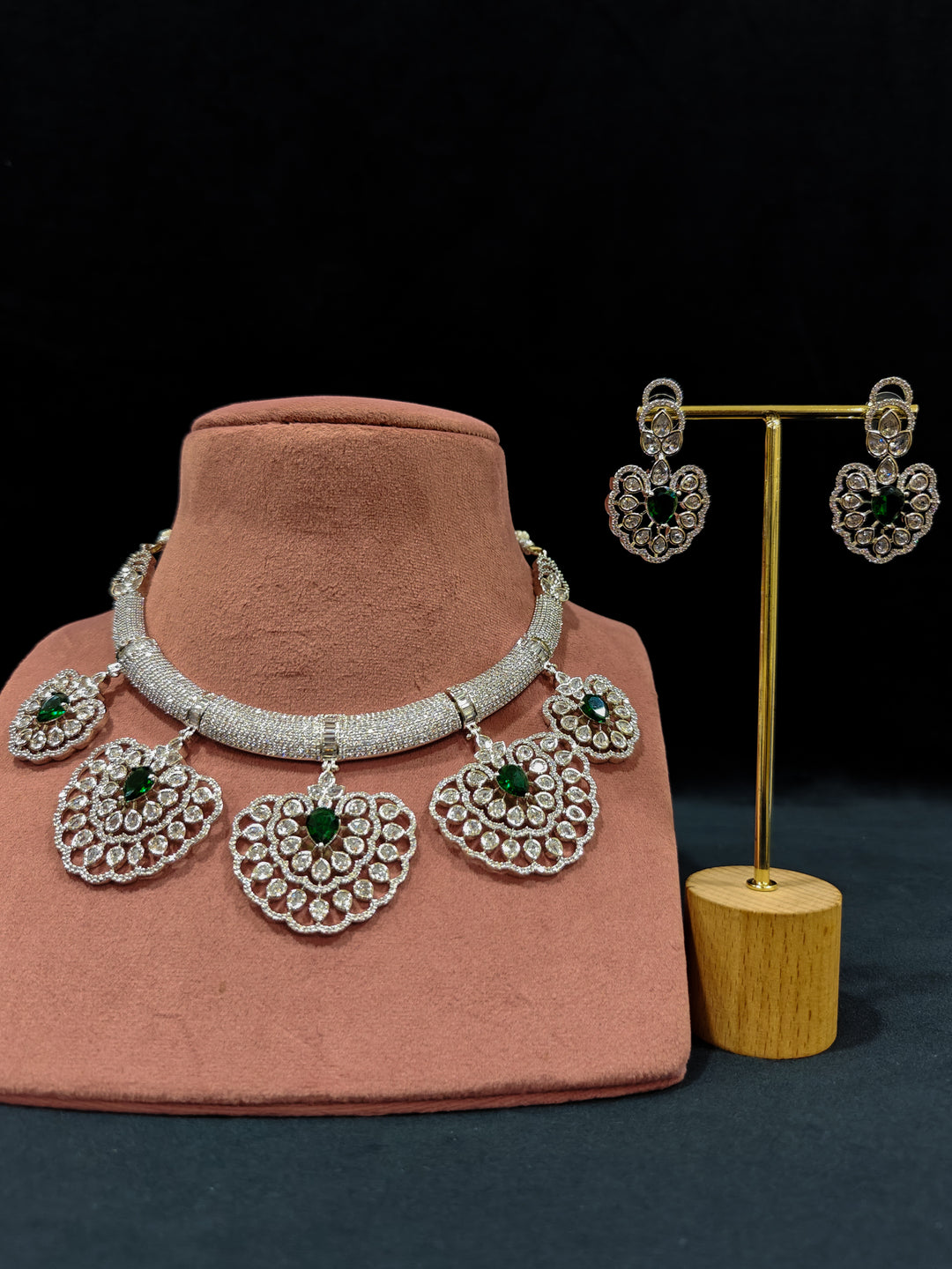 Close-up of a woman wearing an ornate Western American diamond Raizel Emerald Green Necklace Set(Silver Polish) Collar jewellery set and earrings with  Colored Stone and American Diamond. Bride-to-be styled in a premium American diamond artificial necklace for her reception party.