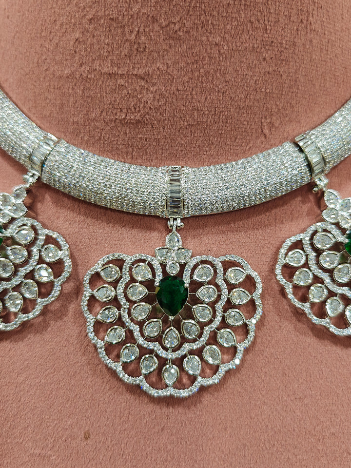 Close-up of a woman wearing an ornate Western American diamond Raizel Emerald Green Necklace Set(Silver Polish) Collar jewellery set and earrings with  Colored Stone and American Diamond. Bride-to-be styled in a premium American diamond artificial necklace for her reception party.