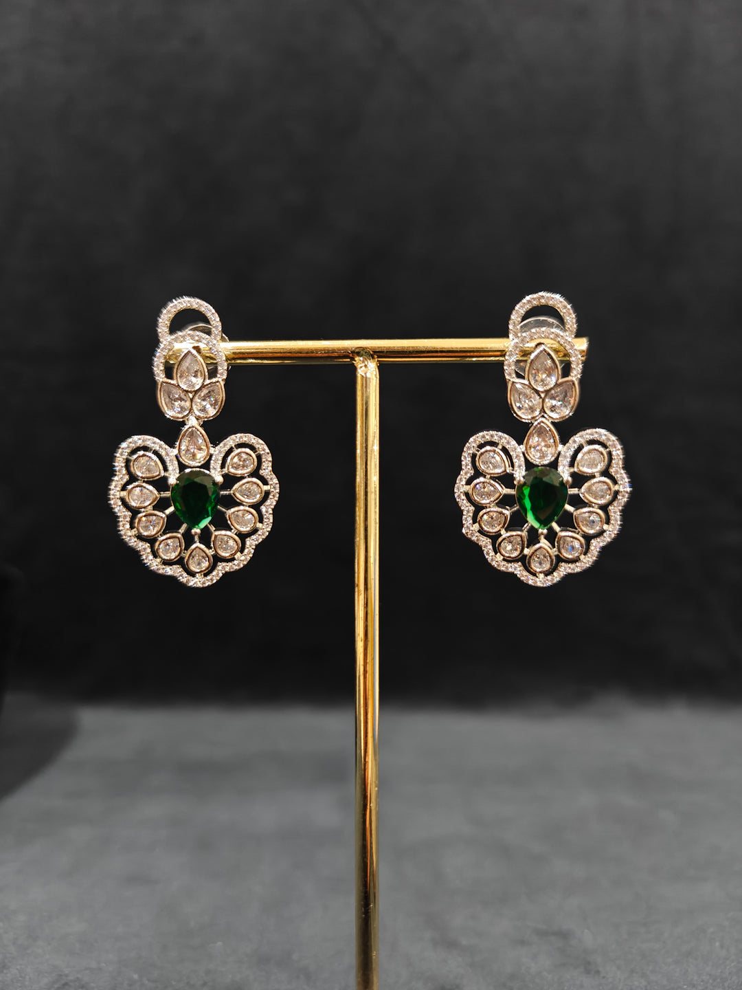 Close-up of a woman wearing an ornate Western American diamond Raizel Emerald Green Necklace Set(Silver Polish) Collar jewellery set and earrings with  Colored Stone and American Diamond. Bride-to-be styled in a premium American diamond artificial necklace for her reception party.