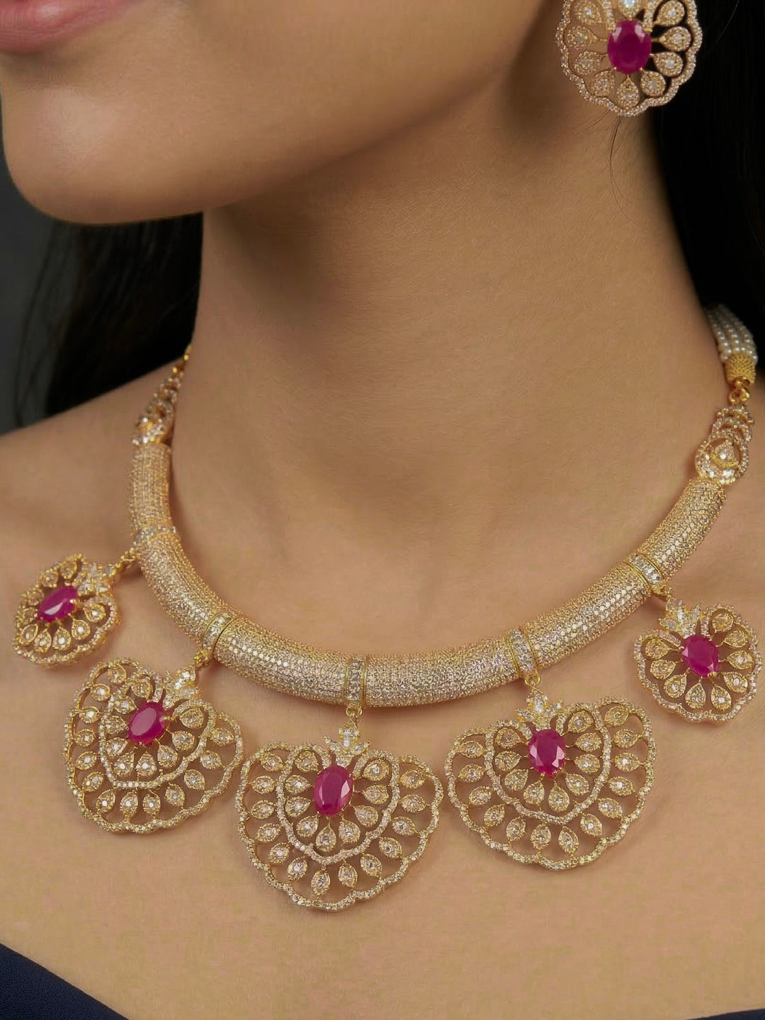 Close-up of a woman wearing an ornate Western American diamond Raizel Ruby Pink Necklace Set (Mehendi Polish) Collar jewellery set and earrings with Colored Stone and American Diamond. Woman styling a statement American diamond necklace with an off-shoulder gown for a reception.