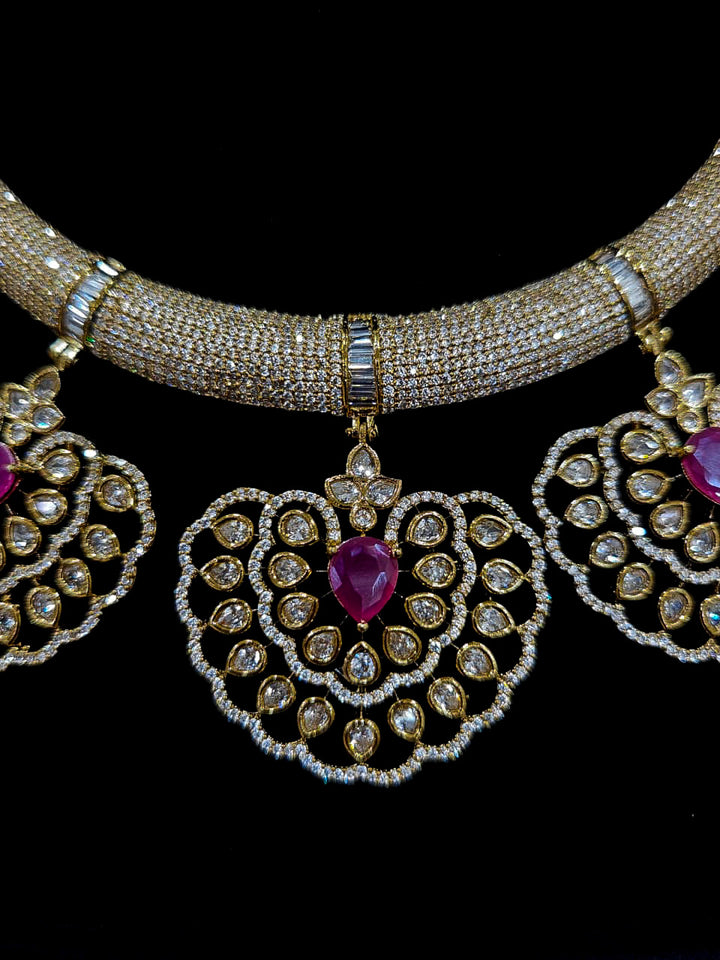 Close-up of an ornate Western American diamond Raizel Ruby Pink Necklace Set (Mehendi Polish) Collar jewellery set and earrings with Colored Stone and American Diamond. Woman styling a statement American diamond necklace with an off-shoulder gown for a reception.