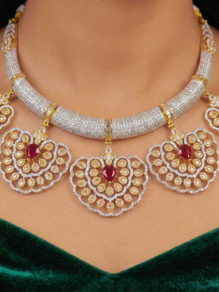Close-up of a woman wearing an ornate Western American diamond Raizel Ruby Red Necklace Set (Dual Tone) Collar jewellery set and earrings with Ruby Red Colored Stone and American Diamond. Bride-to-be styled in a premium American diamond artificial necklace for her reception party.