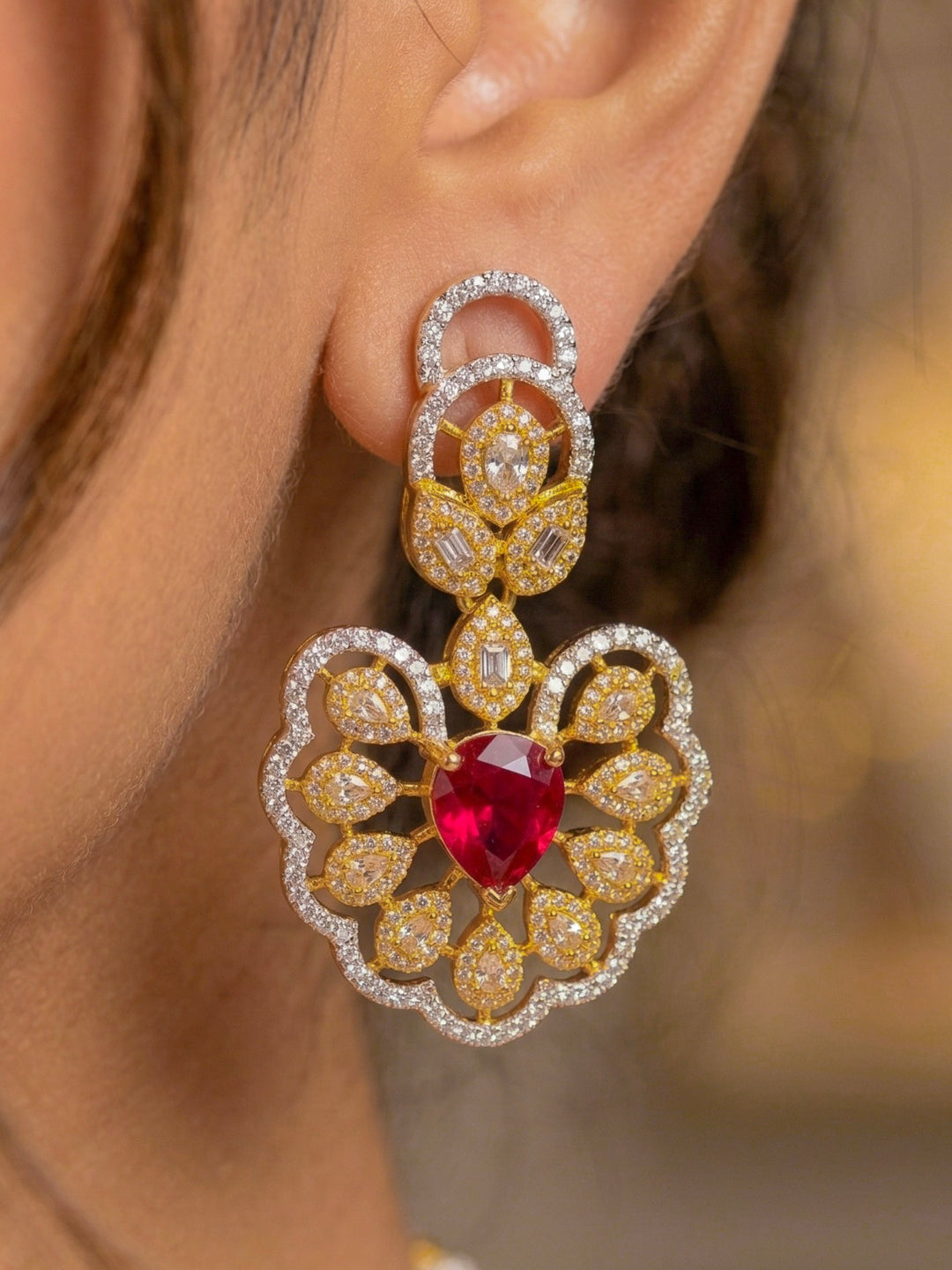 Close-up of a woman wearing an ornate Western American diamond Raizel Ruby Red Necklace Set (Dual Tone) Collar jewellery set and earrings with Ruby Red Colored Stone and American Diamond. Bride-to-be styled in a premium American diamond artificial necklace for her reception party.