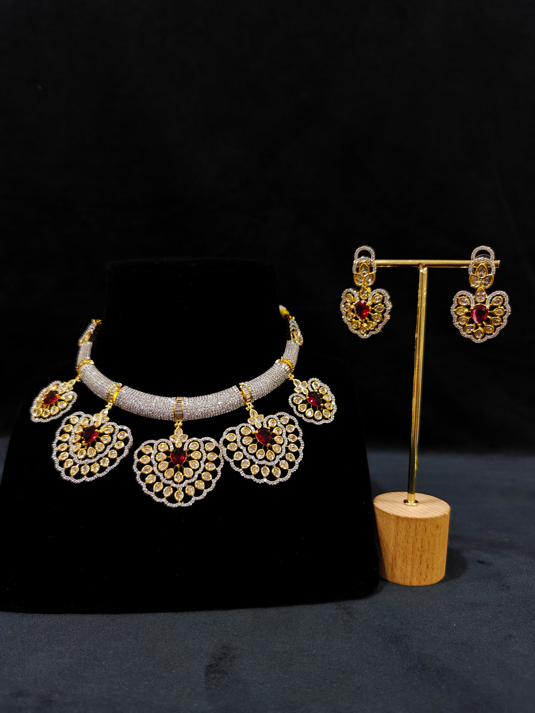 Close-up of an ornate Western American diamond Raizel Ruby Red Necklace Set (Dual Tone) Collar jewellery set and earrings with Ruby Red Colored Stone and American Diamond. Bride-to-be styled in a premium American diamond artificial necklace for her reception party.