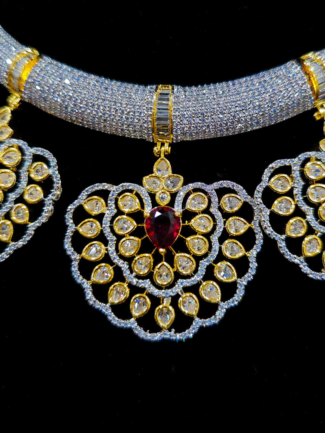 Close-up of an ornate Western American diamond Raizel Ruby Red Necklace Set (Dual Tone) Collar jewellery set and earrings with Ruby Red Colored Stone and American Diamond. Bride-to-be styled in a premium American diamond artificial necklace for her reception party.