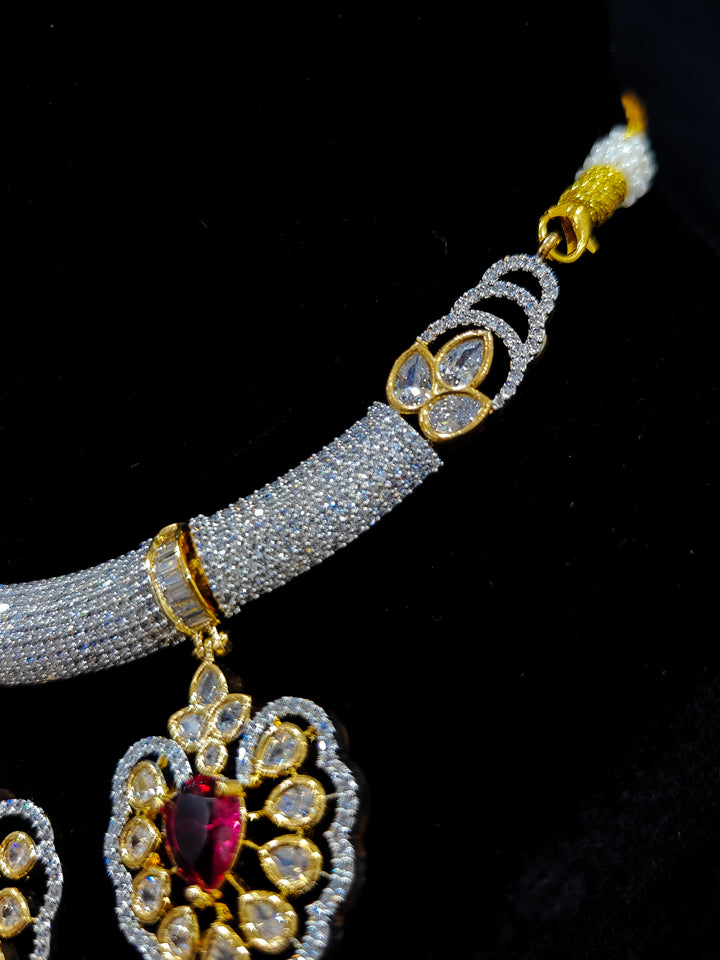 Close-up of an ornate Western American diamond Raizel Ruby Red Necklace Set (Dual Tone) Collar jewellery set and earrings with Ruby Red Colored Stone and American Diamond. Bride-to-be styled in a premium American diamond artificial necklace for her reception party.