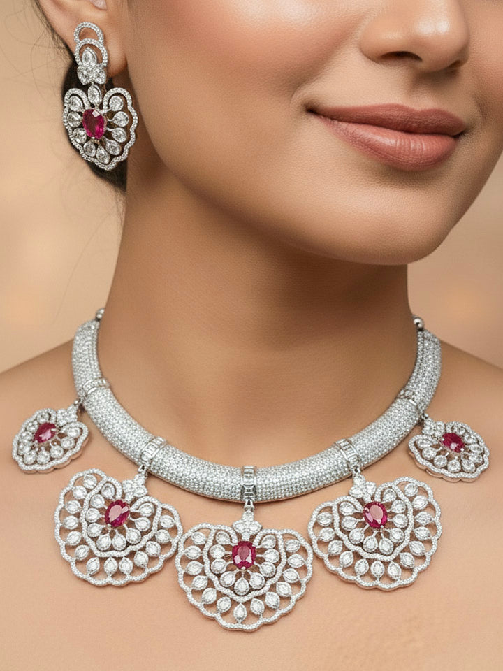 "A bride-to-be wearing an exquisite artificial diamond necklace with ruby red colored stone and matching earrings, designed for the perfect engagement look. This stunning artificial diamond jewelry set offers luxury and sophistication while being an affordable alternative to natural diamonds."