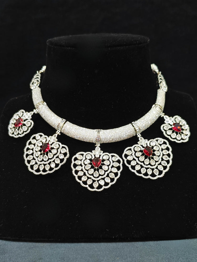 Close-up of an ornate Western American diamond Raizel Ruby Red Necklace Set (Silver Polish) Collar jewellery set and earrings with Colored Stone and American Diamond. Bride-to-be styled in a premium American diamond artificial necklace for her reception party.