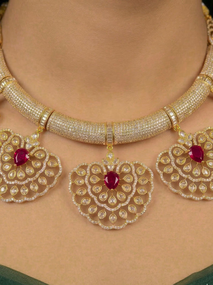 Close-up of a woman wearing an ornate Western American diamond Raizel Ruby red Necklace Set (Mehendi Polish) Collar jewellery set and earrings with Ruby Red Colored Stone and American Diamond. Bride-to-be styled in a premium American diamond artificial necklace for her reception party.