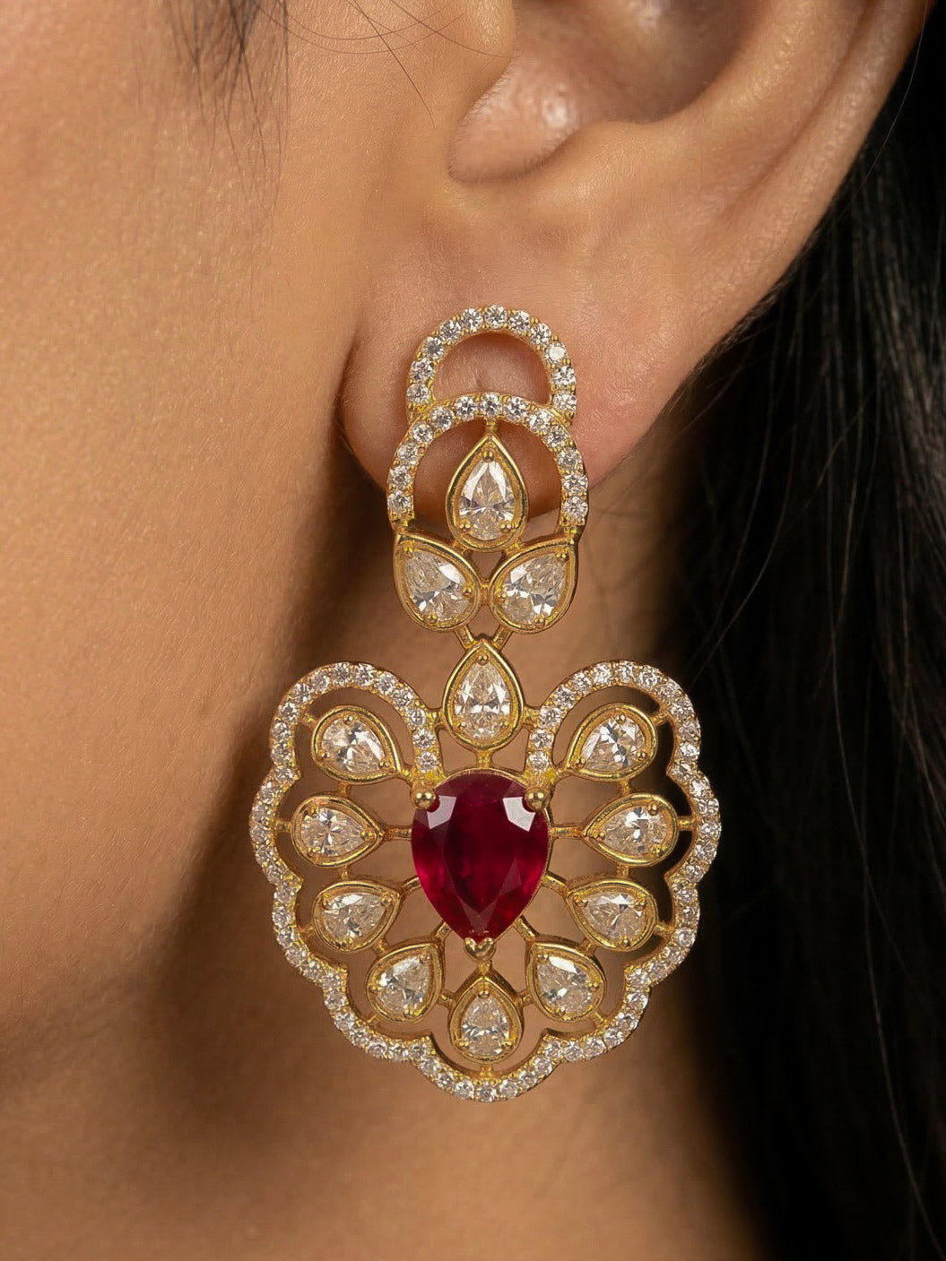 Close-up of a woman wearing an ornate Western American diamond Raizel Ruby red Necklace Set (Mehendi Polish) Collar jewellery set and earrings with Ruby Red Colored Stone and American Diamond. Bride-to-be styled in a premium American diamond artificial necklace for her reception party.