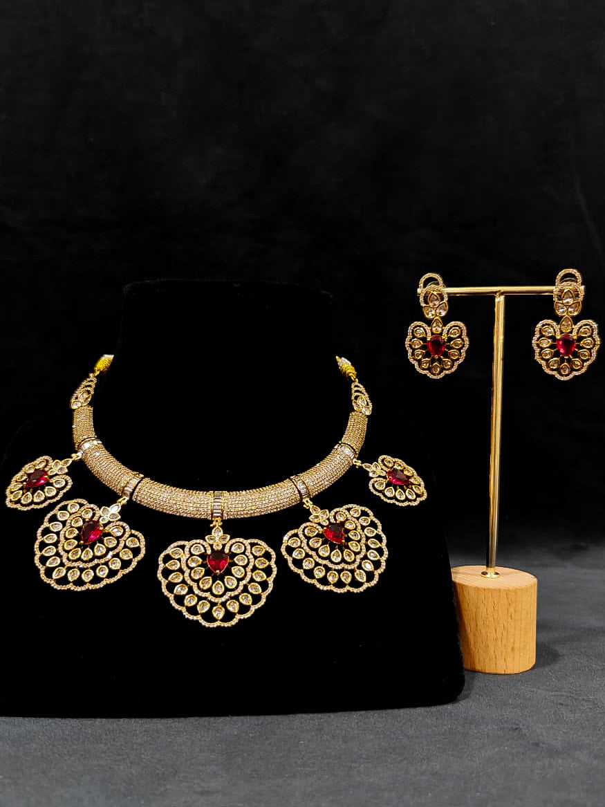 Close-up of an ornate Western American diamond Raizel Ruby red Necklace Set (Mehendi Polish) Collar jewellery set and earrings with Ruby Red Colored Stone and American Diamond. Bride-to-be styled in a premium American diamond artificial necklace for her reception party.