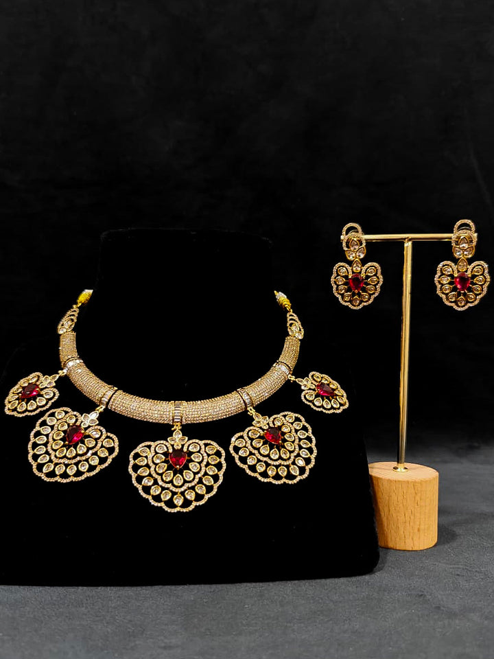 Close-up of an ornate Western American diamond Raizel Ruby red Necklace Set (Mehendi Polish) Collar jewellery set and earrings with Ruby Red Colored Stone and American Diamond. Bride-to-be styled in a premium American diamond artificial necklace for her reception party.