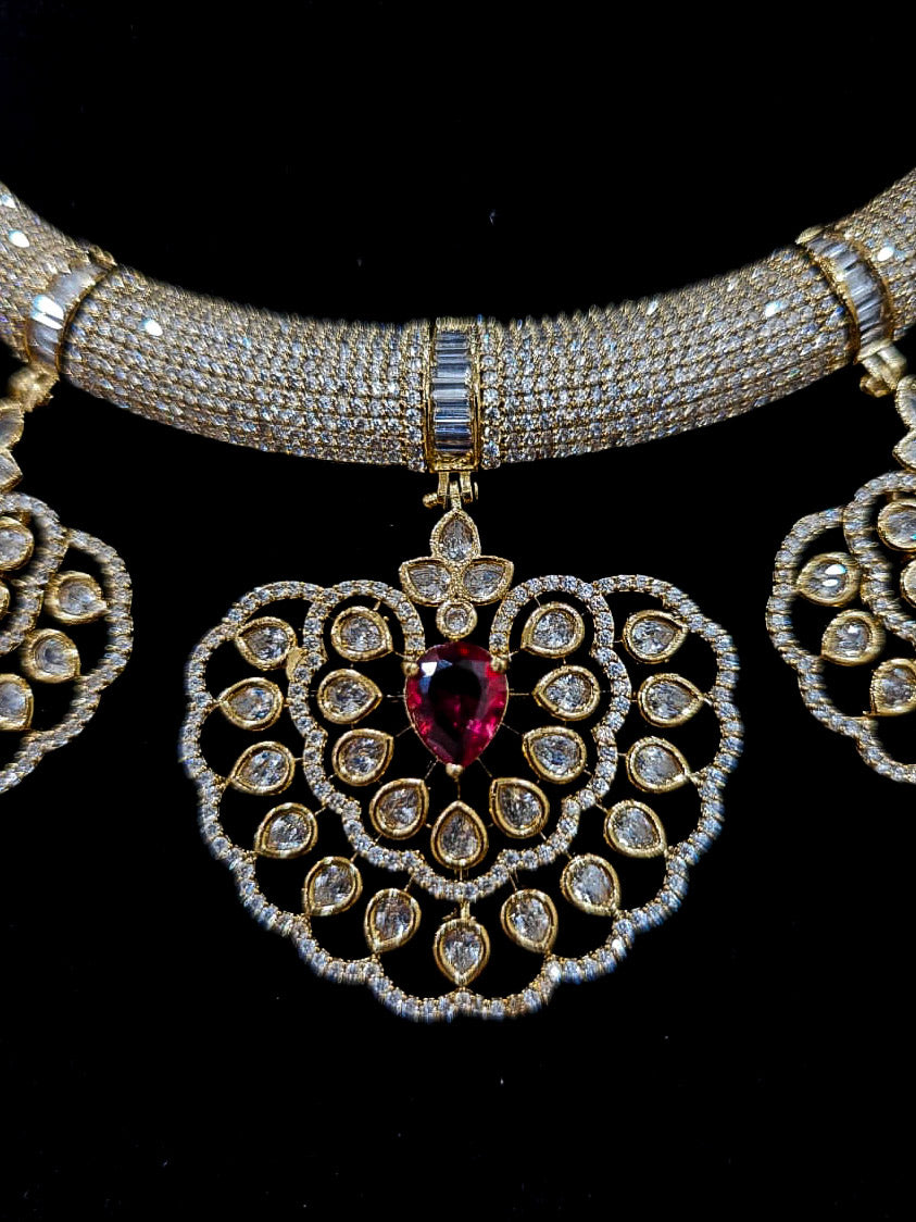 Close-up of an ornate Western American diamond Raizel Ruby red Necklace Set (Mehendi Polish) Collar jewellery set and earrings with Ruby Red Colored Stone and American Diamond. Bride-to-be styled in a premium American diamond artificial necklace for her reception party.