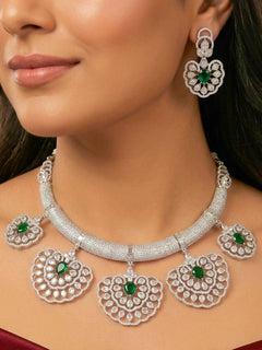 Close-up of a woman wearing an ornate Western American diamond Raizel Emerald Green Necklace Set(Silver Polish) Collar jewellery set and earrings with  Colored Stone and American Diamond. Bride-to-be styled in a premium American diamond artificial necklace for her reception party.