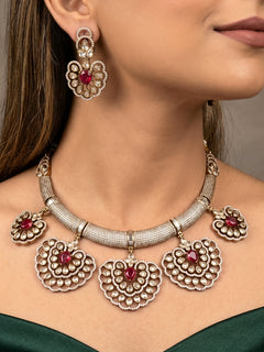 Close-up of a woman wearing an ornate Western American diamond Raizel Ruby red Necklace Set (Mehendi Polish) Collar jewellery set and earrings with Ruby Red Colored Stone and American Diamond. Bride-to-be styled in a premium American diamond artificial necklace for her reception party.