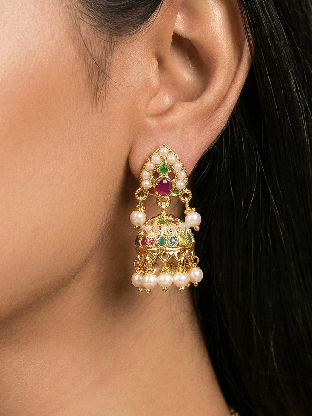 Close-up of a woman wearing an ornate traditional Navratan jadau gold jewellery set and jadau earrings with Pearls and Navratan Stones. Woman pairing a traditional Jadau necklace with a silk saree. Woman wearing a premium Jadau artificial jewelry set for reception night.