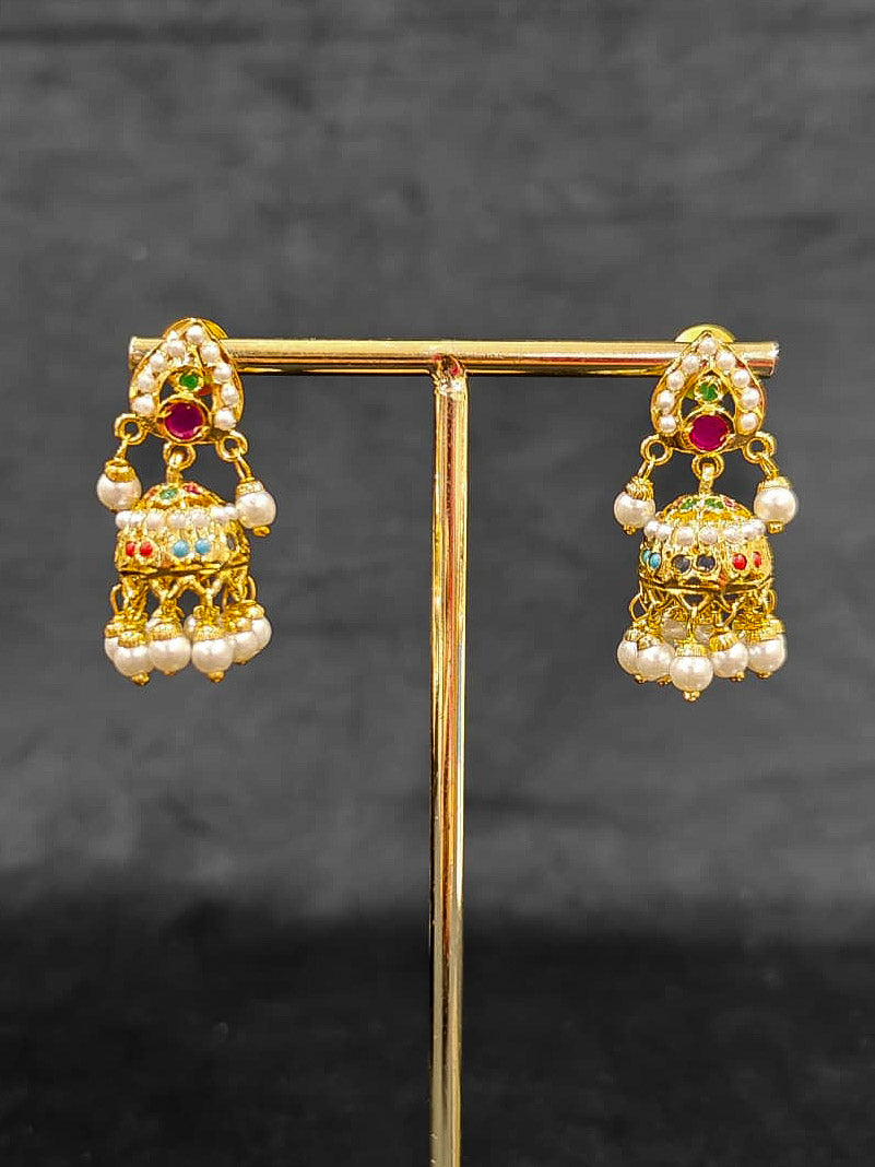 Close-up of an ornate traditional Navratan jadau gold jewellery set and jadau earrings with Pearls and Navratan Stones. Elegant reception look featuring a luxury Jadau artificial jewelry set. Festive celebration look featuring a Jadau artificial necklace.