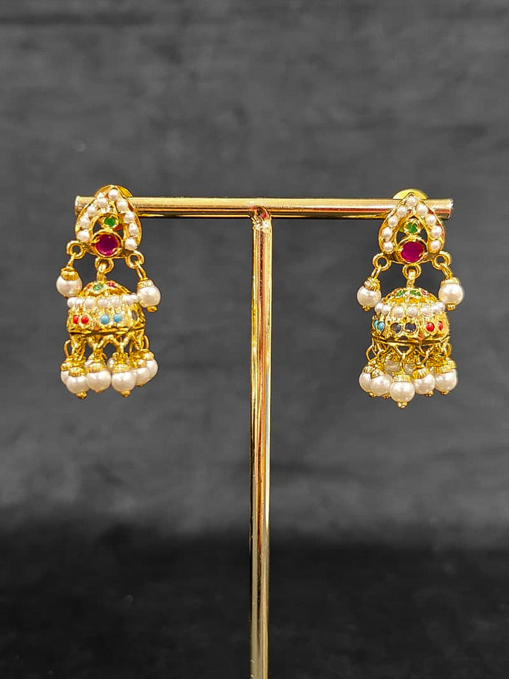 Close-up of an ornate traditional Navratan jadau gold jewellery set and jadau earrings with Pearls and Navratan Stones. Elegant reception look featuring a luxury Jadau artificial jewelry set. Festive celebration look featuring a Jadau artificial necklace.