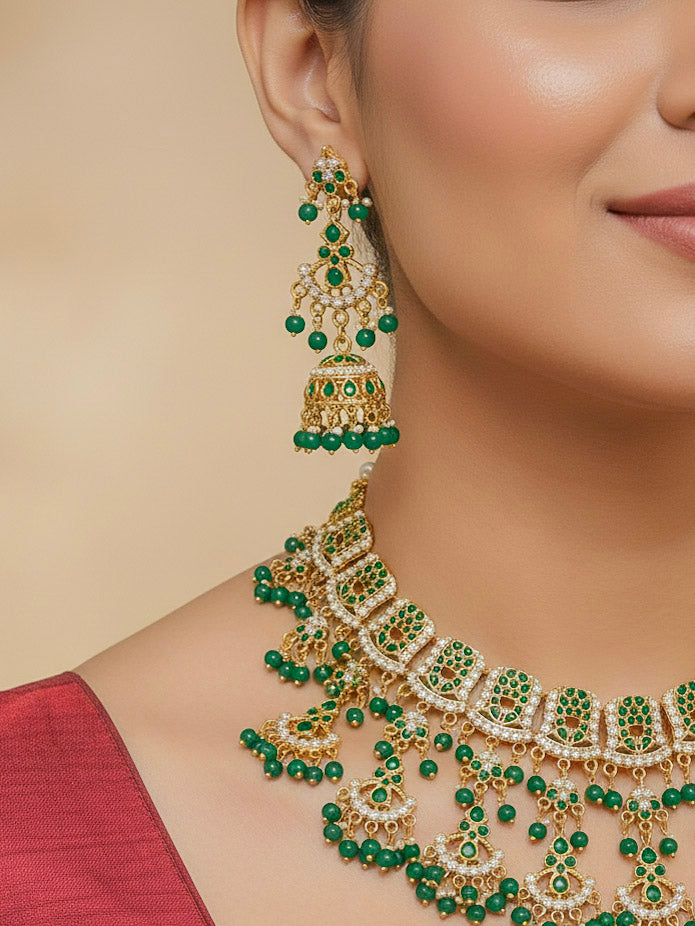 Close-up of a woman wearing an elaborate green and gold jadau necklace with matched earring for wedding celebrations. Woman pairing a traditional Jadau necklace with a silk saree.Woman wearing a royal Jadau necklace for festive events in India.
