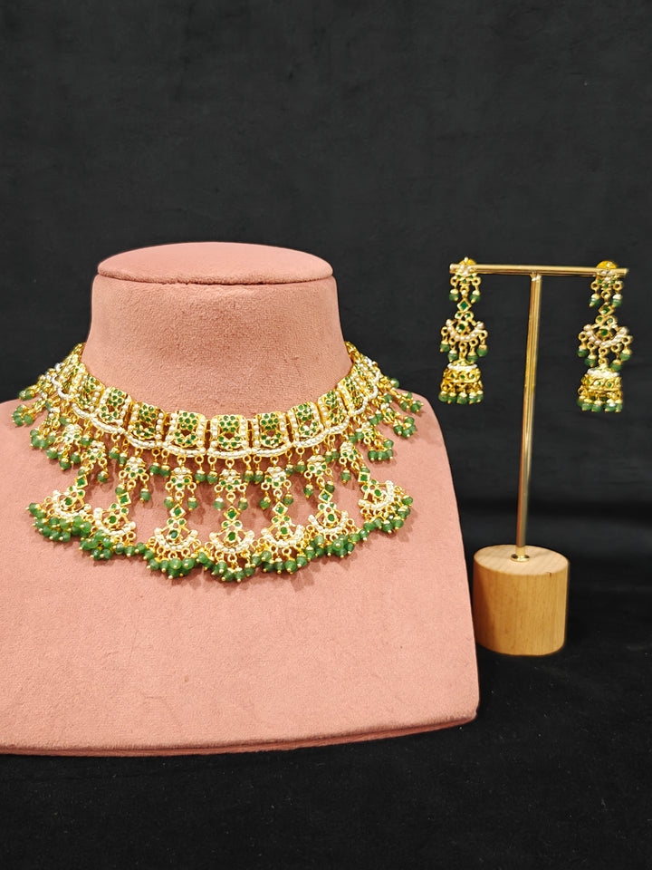 Close-up of an ornate traditional jadau gold jewellery set and jadau earrings with Beads and gemstones. Woman pairing a traditional Jadau necklace with a silk saree.Woman wearing a royal Jadau necklace for festive events in India.