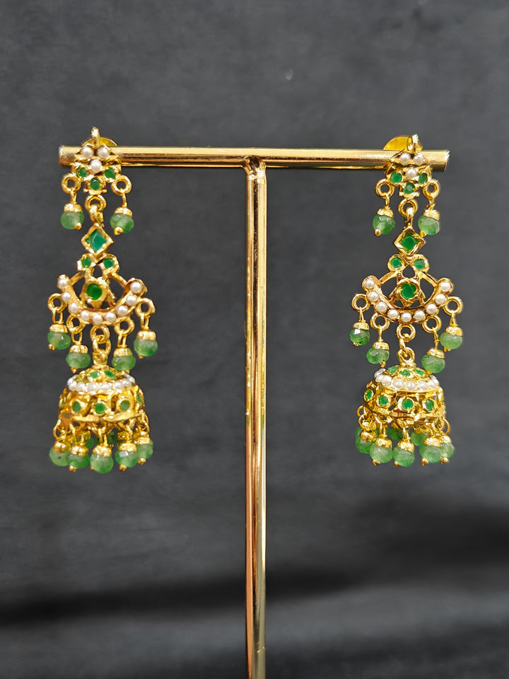 Close-up of an ornate traditional jadau gold jewellery set and jadau earrings with Beads and gemstones. Woman pairing a traditional Jadau necklace with a silk saree.Woman wearing a royal Jadau necklace for festive events in India.