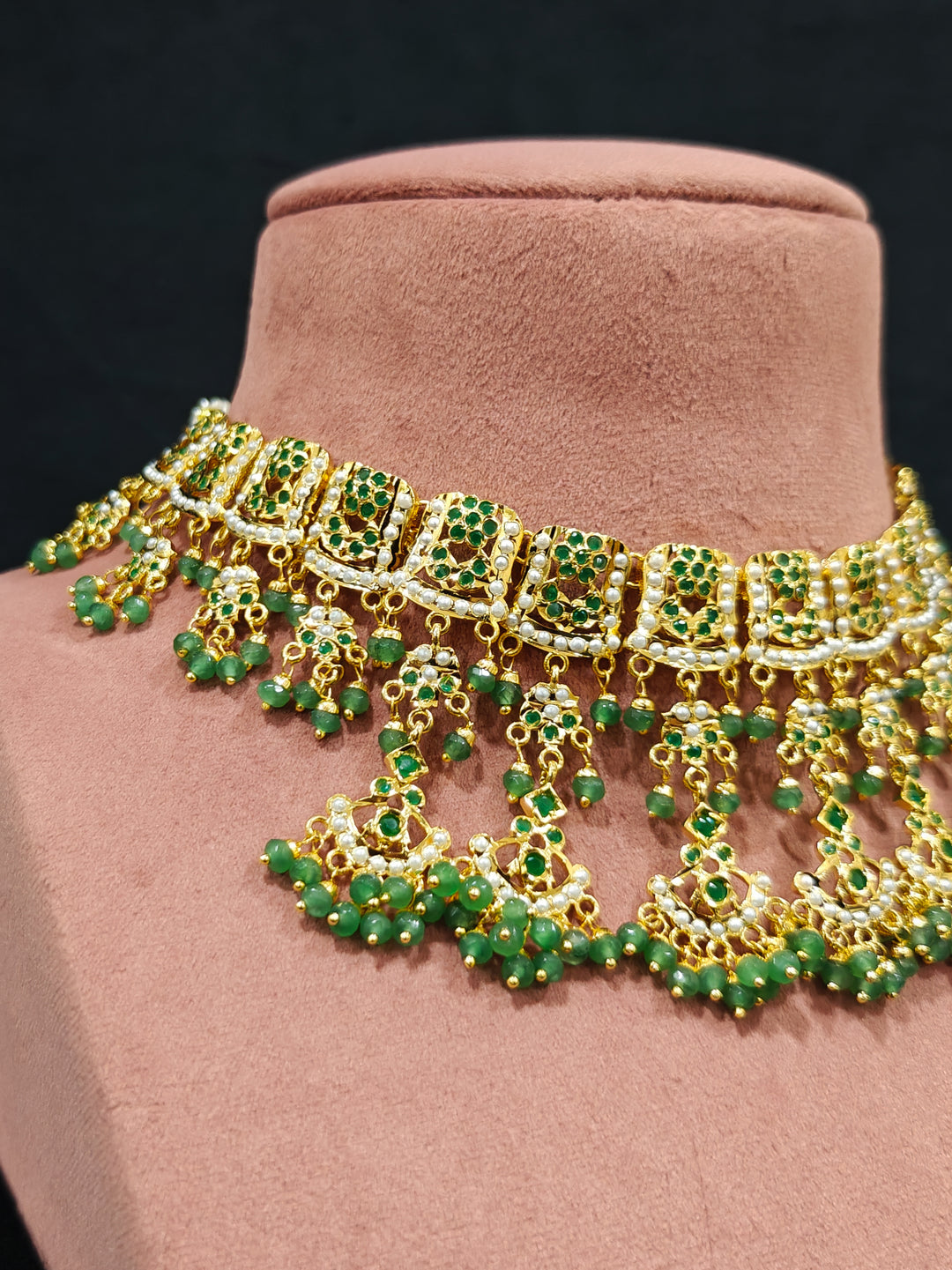 Close-up of an ornate traditional jadau gold jewellery set and jadau earrings with Beads and gemstones. Woman pairing a traditional Jadau necklace with a silk saree.Woman wearing a royal Jadau necklace for festive events in India.