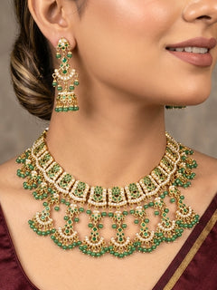 Close-up of a woman wearing an ornate traditional jadau gold jewellery set and jadau earrings with Beads and gemstones. Woman pairing a traditional Jadau necklace with a silk saree.Woman wearing a royal Jadau necklace for festive events in India.