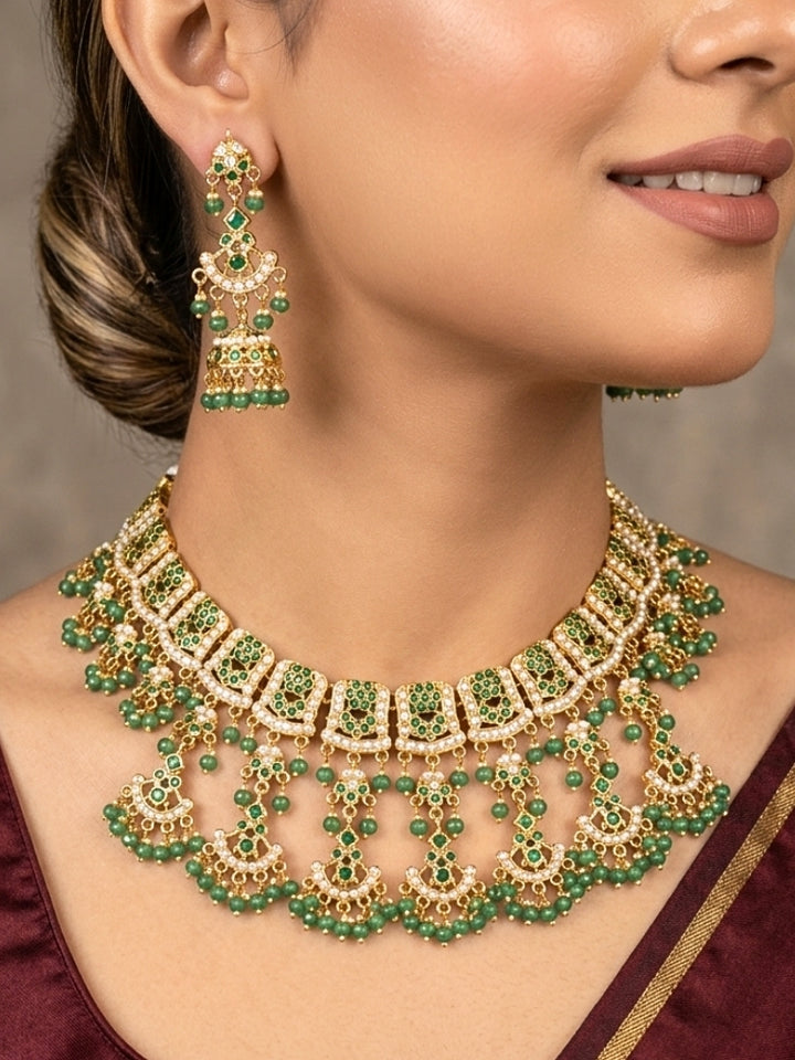 Close-up of a woman wearing an ornate traditional jadau gold jewellery set and jadau earrings with Beads and gemstones. Woman pairing a traditional Jadau necklace with a silk saree.Woman wearing a royal Jadau necklace for festive events in India.