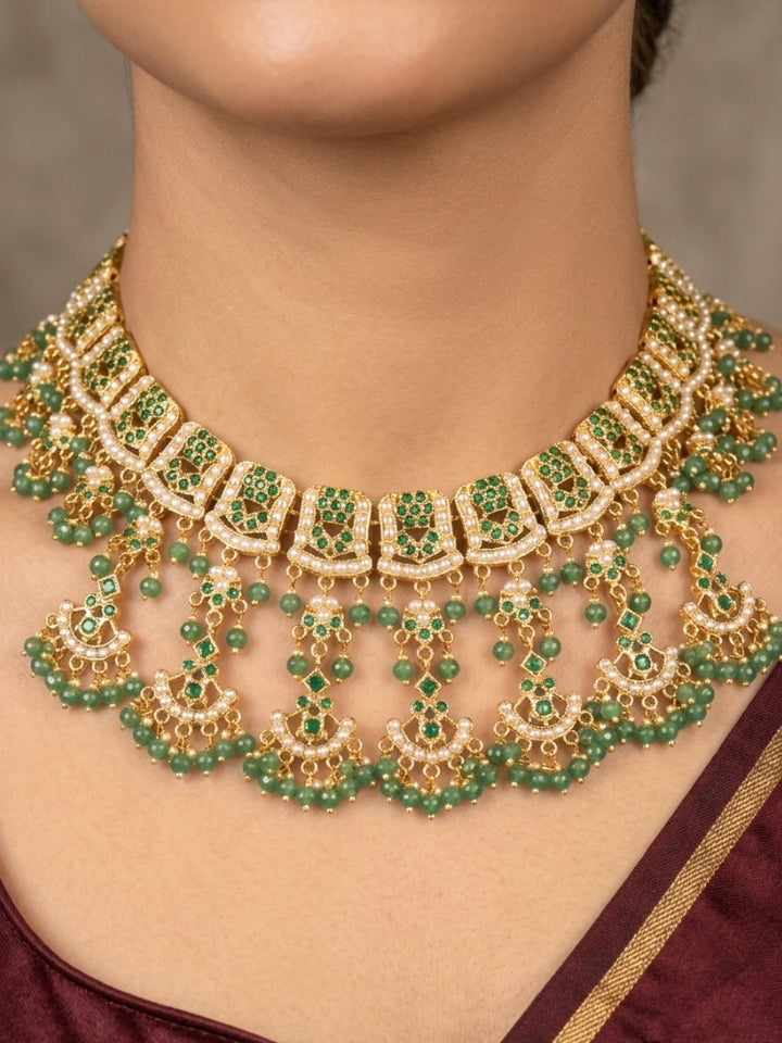 Close-up of a woman wearing an ornate traditional jadau gold jewellery set and jadau earrings with Beads and gemstones. Woman pairing a traditional Jadau necklace with a silk saree.Woman wearing a royal Jadau necklace for festive events in India.