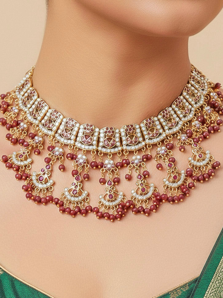 Close-up of a woman wearing an ornate traditional Ruby Pink jadau gold jewellery set and jadau earrings with Beads and gemstones. Close-up of a luxury Jadau imitation necklace styled with a bridal lehenga.Bride wearing a luxury Jadau necklace for her reception ceremony.
