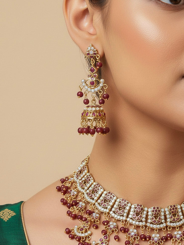 Close-up of a woman wearing an ornate traditional Ruby Pink jadau gold jewellery set and jadau earrings with Beads and gemstones. Close-up of a luxury Jadau imitation necklace styled with a bridal lehenga.Bride wearing a luxury Jadau necklace for her reception ceremony.
