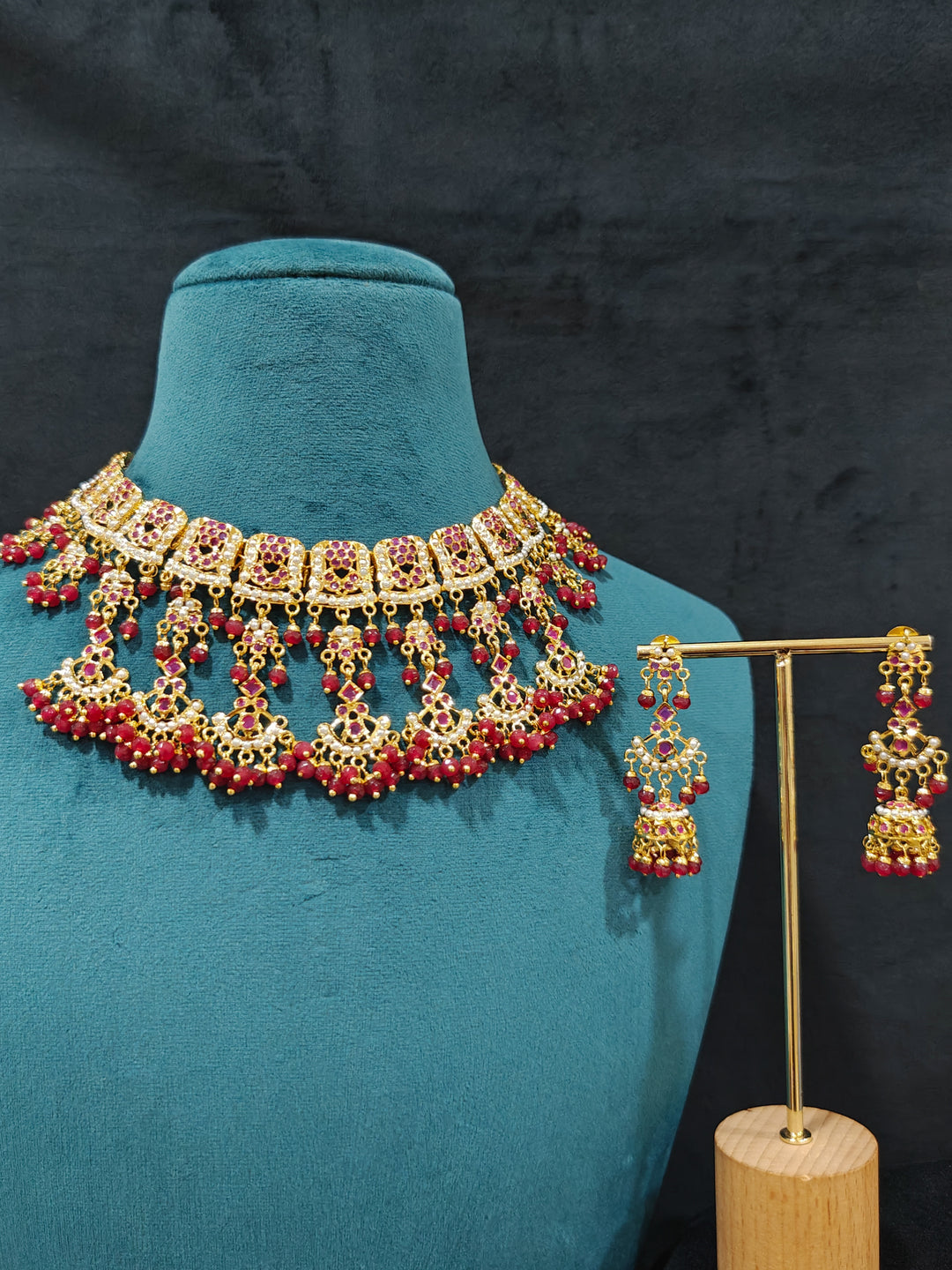 Close-up of an ornate traditional Ruby Pink jadau gold jewellery set and jadau earrings with Beads and gemstones. Close-up of a luxury Jadau imitation necklace styled with a bridal lehenga .Statement Jadau necklace styled for a wedding guest outfit.