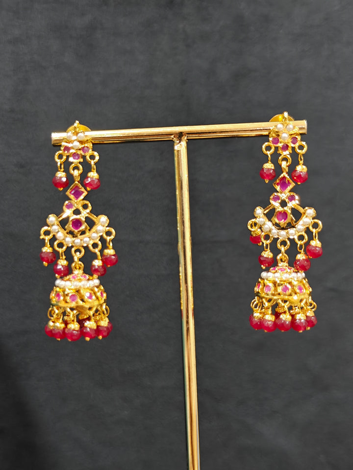 Close-up of an ornate traditional Ruby Pink jadau gold jewellery set and jadau earrings with Beads and gemstones. Close-up of a luxury Jadau imitation necklace styled with a bridal lehenga .Statement Jadau necklace styled for a wedding guest outfit.