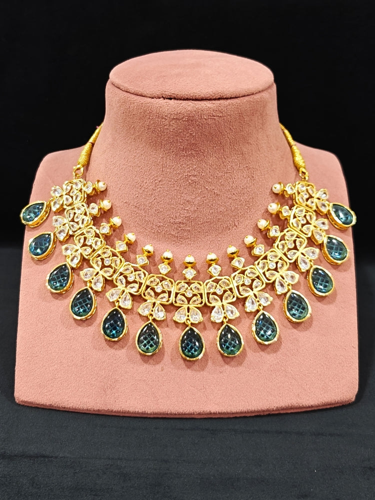 Close-up of an ornate traditional (Gold Polish) Blue Collar jewellery set and earrings with Diamond Polki, Monalisa Stone and Colored Stones. Wedding guest wearing a sparkling American diamond necklace with a saree. A graceful woman wearing a trending American diamond necklace for a 2026 wedding celebration.
