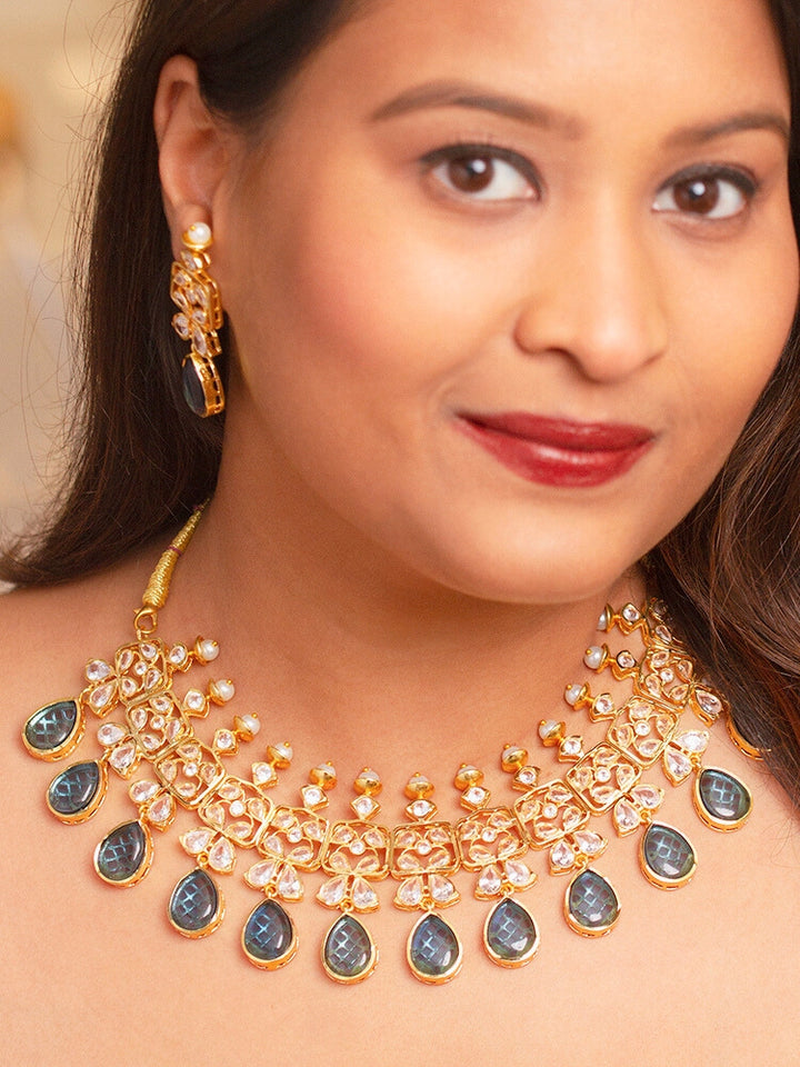 Close-up of a woman wearing an ornate traditional (Gold Polish) Blue Collar jewellery set and earrings with Diamond Polki, Monalisa Stone and Colored Stones. Wedding guest wearing a sparkling American diamond necklace with a saree. A graceful woman wearing a trending American diamond necklace for a 2026 wedding celebration.