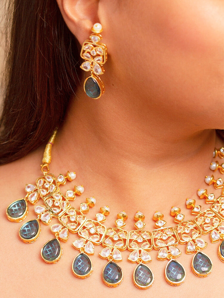 Close-up of a woman wearing an ornate traditional (Gold Polish) Blue Collar jewellery set and earrings with Diamond Polki, Monalisa Stone and Colored Stones. Wedding guest wearing a sparkling American diamond necklace with a saree. A graceful woman wearing a trending American diamond necklace for a 2026 wedding celebration.