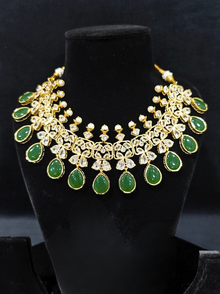 Close-up of an ornate traditional (Gold Polish) Dark Green Collar jewellery set and earrings with Diamond Polki, Monalisa Stone and Colored Stones. Wedding guest wearing a sparkling American diamond necklace with a saree. A graceful woman wearing a trending American diamond necklace for a 2026 wedding celebration.