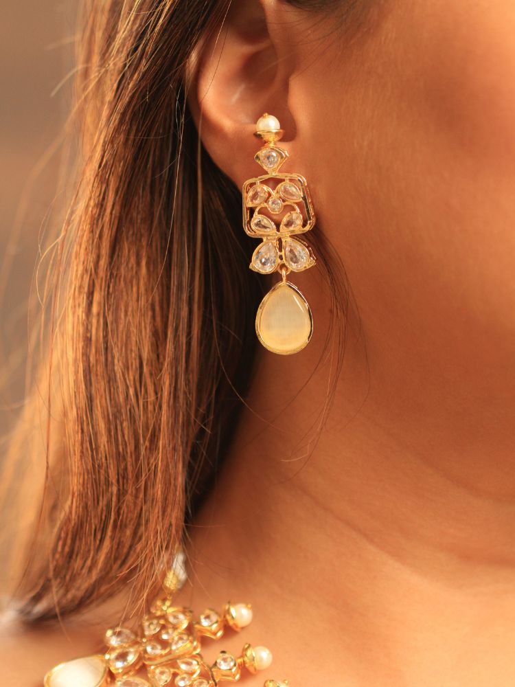 A woman radiates traditional elegance wearing the Rani Kundan Necklace Set with Ivory stones, complete with matching earrings. She smiles softly in an ornate, embroidered outfit accented by mirror embellishments.