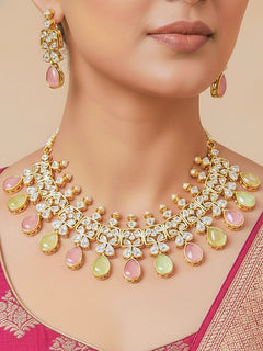 Close-up of a woman wearing an ornate traditional (Gold Polish) Pink & Green Collar jewellery set and earrings with Diamond Polki, Monalisa Stone and Colored Stones. Wedding guest wearing a sparkling American diamond necklace with a saree. A graceful woman wearing a trending American diamond necklace for a 2026 wedding celebration.