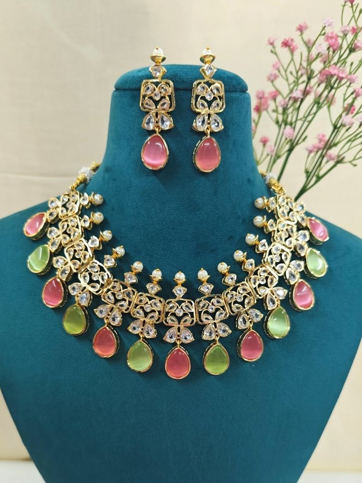 Close-up of an ornate traditional (Gold Polish) Pink & Green Collar jewellery set and earrings with Diamond Polki, Monalisa Stone and Colored Stones. Wedding guest wearing a sparkling American diamond necklace with a saree. A graceful woman wearing a trending American diamond necklace for a 2026 wedding celebration.