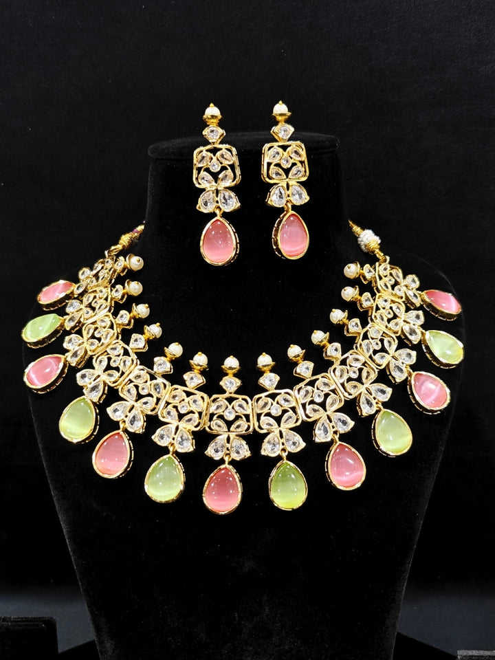 Close-up of an ornate traditional (Gold Polish) Pink & Green Collar jewellery set and earrings with Diamond Polki, Monalisa Stone and Colored Stones. Wedding guest wearing a sparkling American diamond necklace with a saree. A graceful woman wearing a trending American diamond necklace for a 2026 wedding celebration.